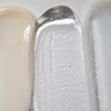 Een close-up afbeelding toont de texturen van Solawaves LightBoost Wand Activating Serum, met romig beige, transparante gel verrijkt met LightBoost technologie, en gladde lichtgrijs/witte crème. De texturen variëren van romig tot gel-achtig, met een glanzende afwerking.